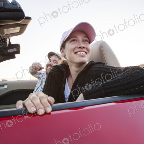 Caucasian couple parked in their sports car convertible.