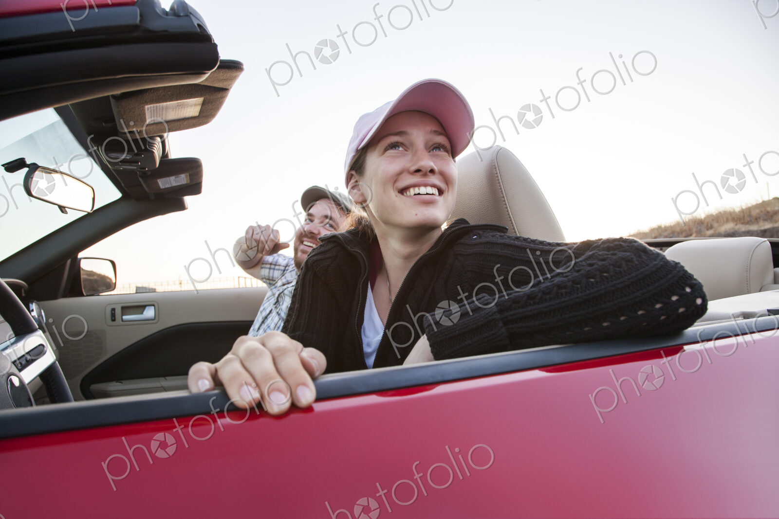 Caucasian couple parked in their sports car convertible.