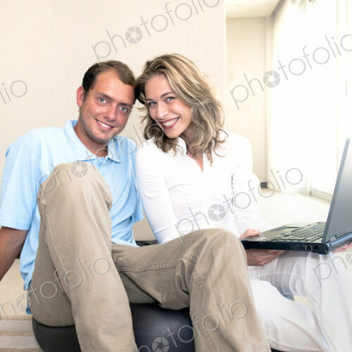 Caucasian couple using laptop on ball on floor