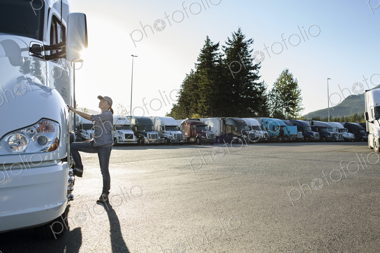 Caucasian female truck driver getting into her truck parked in a lot at a truck stop.
