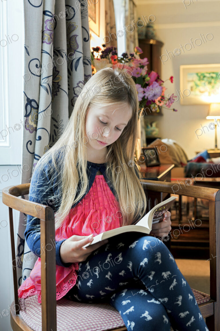 Caucasian girl reading book in armchair