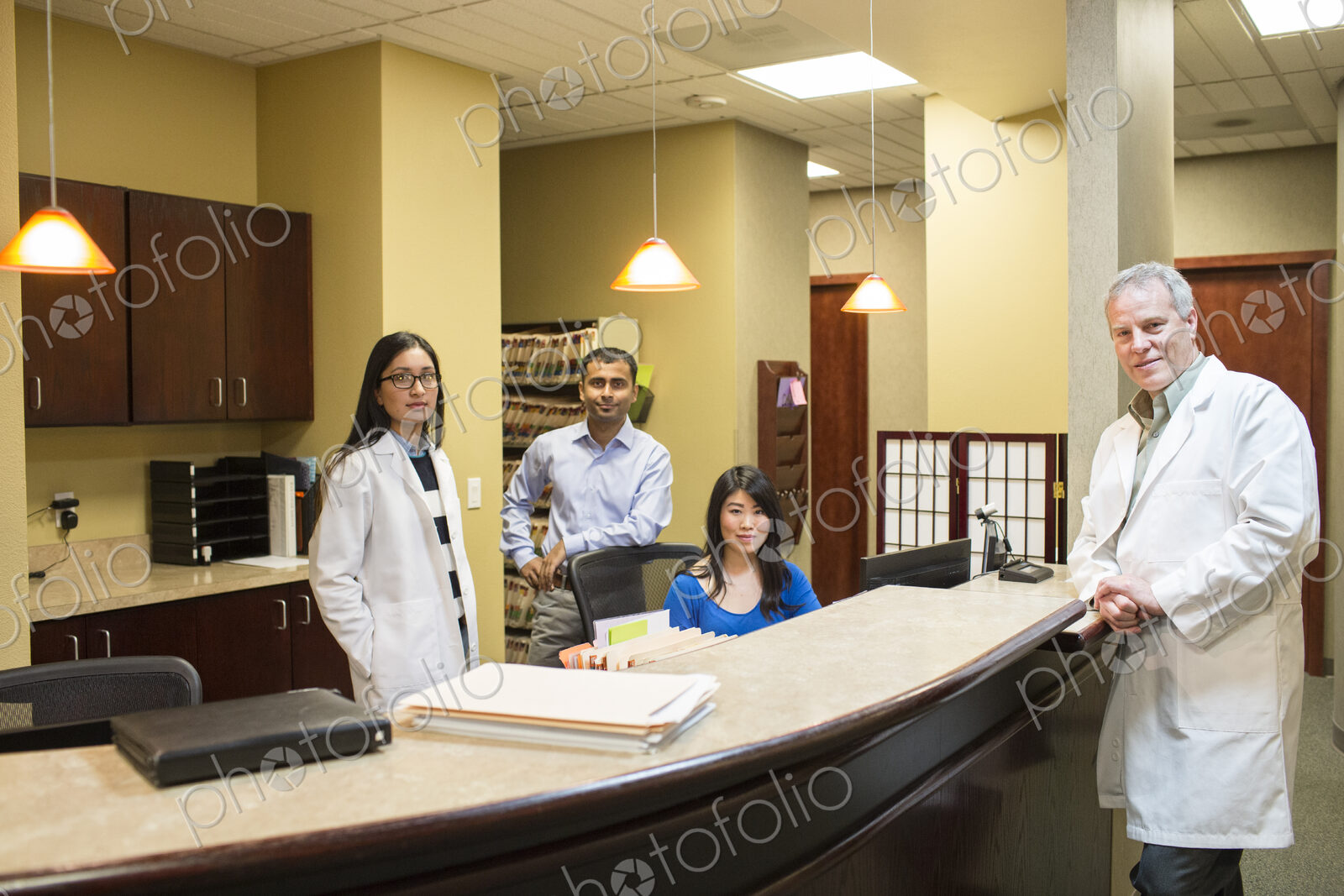 Caucasian male and east Indian woman ophthalmologists in their office with their staff…