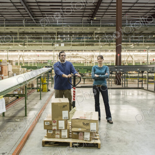 Caucasian male and female workers in a large distribution warehouse. Caucasian male and female workers in a large distribution warehouse.
