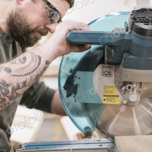 Caucasian male carpenter using a radial saw to cut a piece of wood in a large… Caucasian male carpenter using a radial saw to cut a piece of wood in a large…