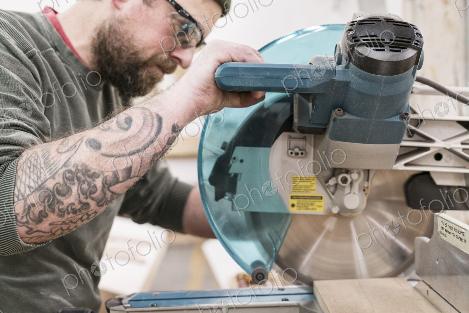 Caucasian male carpenter using a radial saw to cut a piece of wood in a large…
