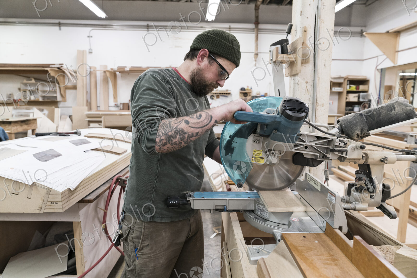 Caucasian male carpenter using a radial saw to cut a piece of wood in a large…