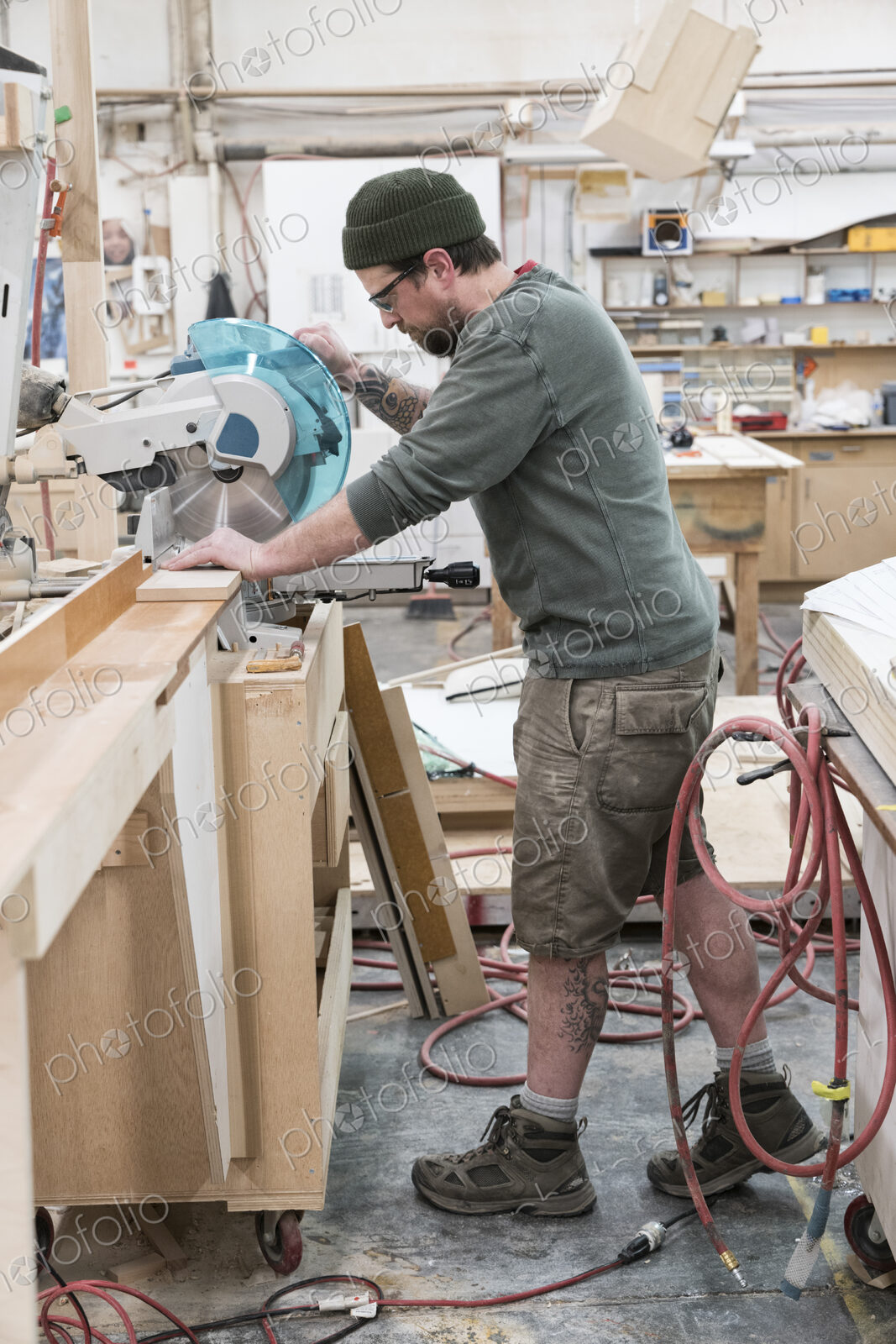 Caucasian male carpenter using a radial saw to cut a piece of wood in a large…