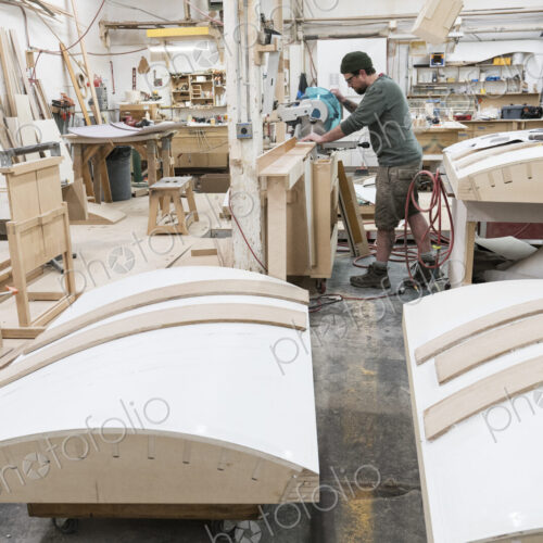 Caucasian male carpenter using a radial saw to cut a piece of wood in a large… Caucasian male carpenter using a radial saw to cut a piece of wood in a large…