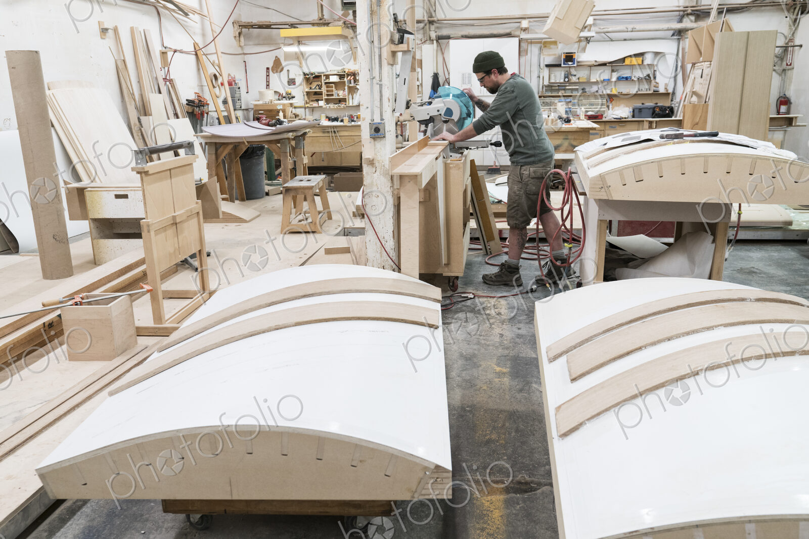 Caucasian male carpenter using a radial saw to cut a piece of wood in a large…