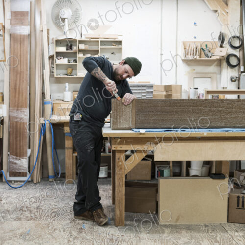 Caucasian male carpenter working on a large cabinet in a woodworking factory