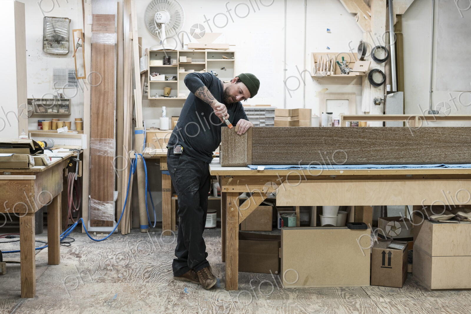 Caucasian male carpenter working on a large cabinet in a woodworking factory