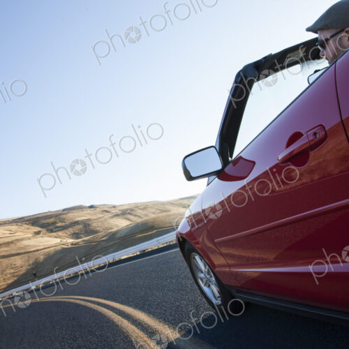 Caucasian male driving a convertible sports car on a road trip in eastern Washington…