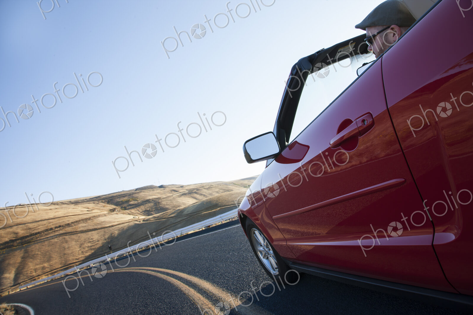 Caucasian male driving a convertible sports car on a road trip in eastern Washington…