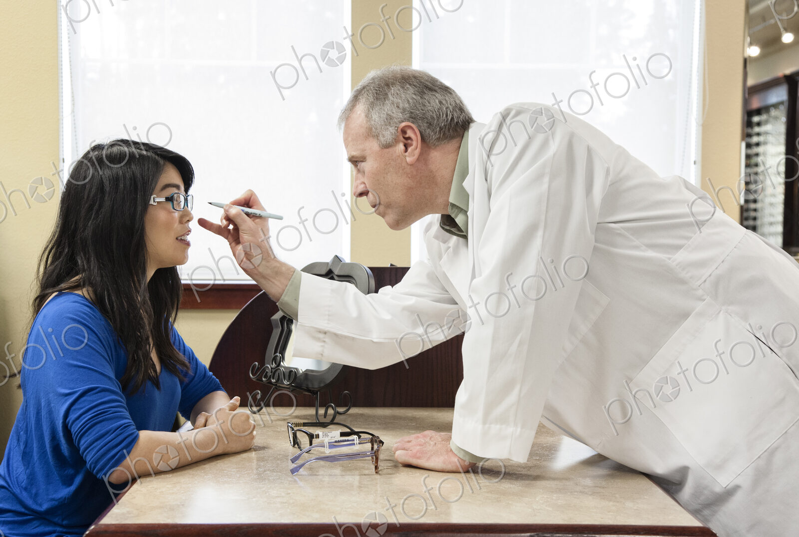 Caucasian male ophthalmologist working with an asian woman who is purchasing a new…