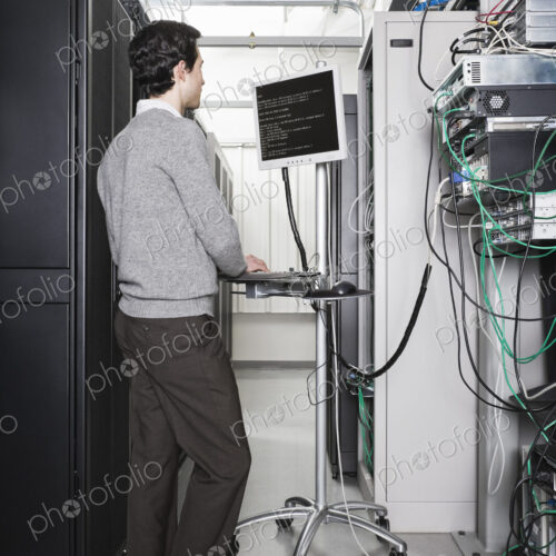 Caucasian male technician working on computer servers in a computer server farm.