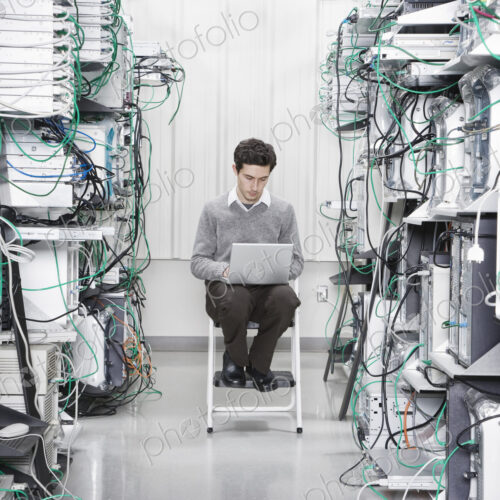Caucasian male technician working on computer servers in a computer server farm.