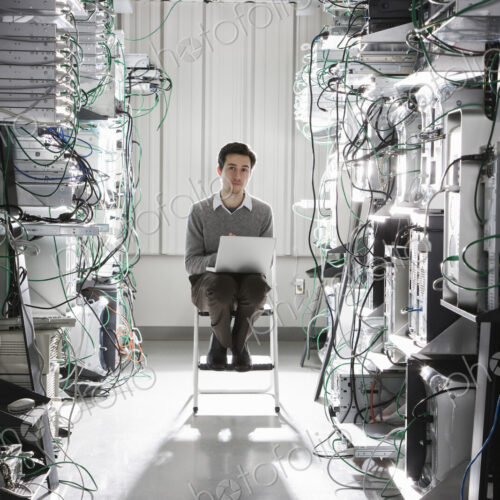 Caucasian male technician working on computer servers in a computer server farm.