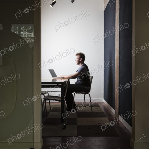 Caucasian male worker using a laptop computere at a conference room table Caucasian male worker using a laptop computere at a conference room table