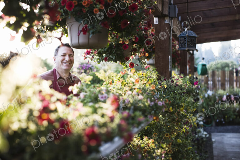 Caucasian man, a garden centre business owner standing among flowering plants in early…