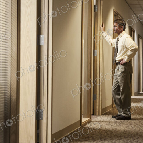 Caucasian man a hallway meeting with another person in an office.