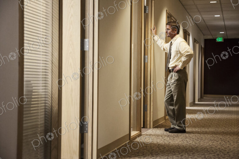 Caucasian man a hallway meeting with another person in an office.
