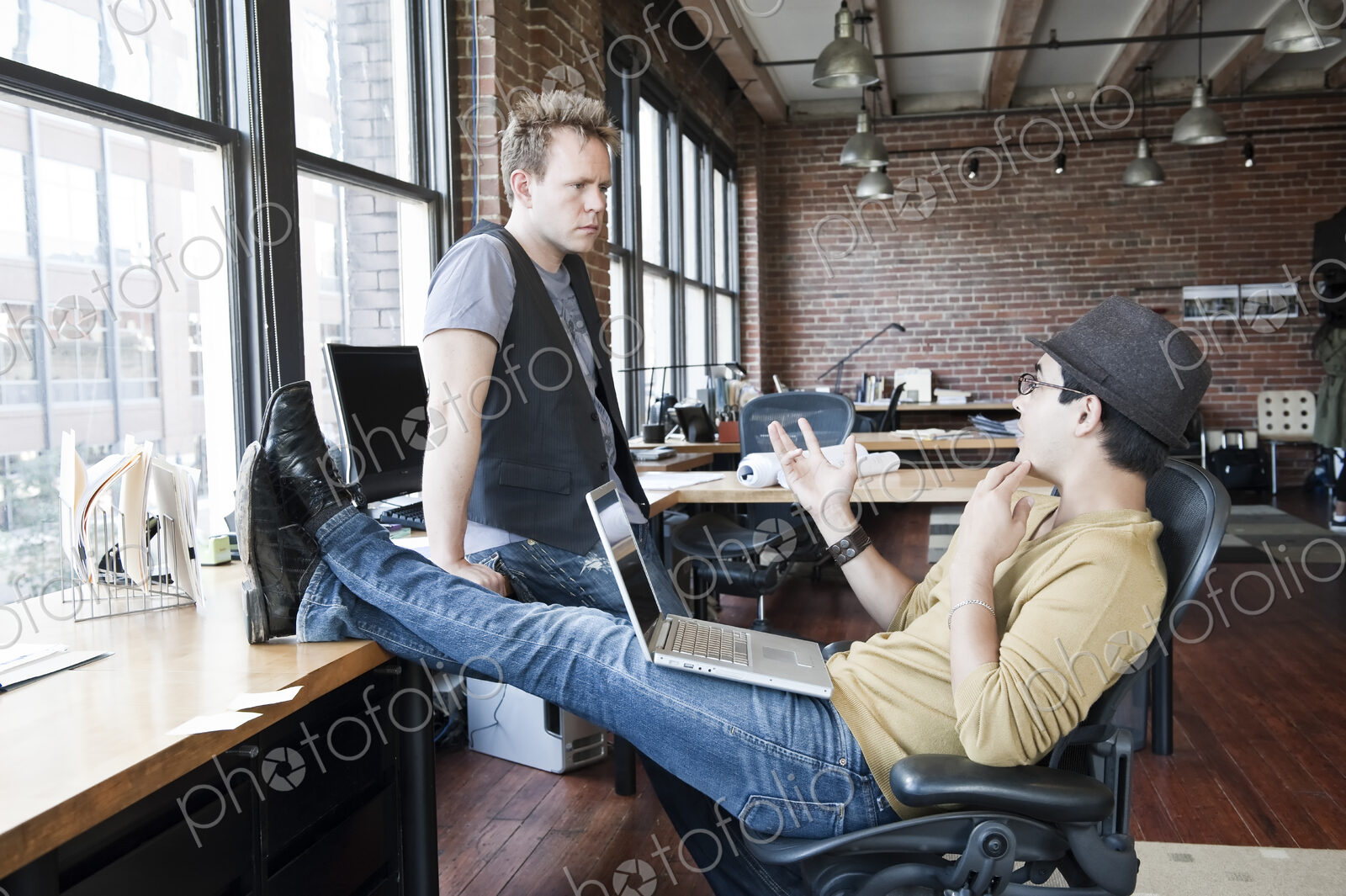 Caucasian man and Hispanic man discussing a problem at a creative office work station.