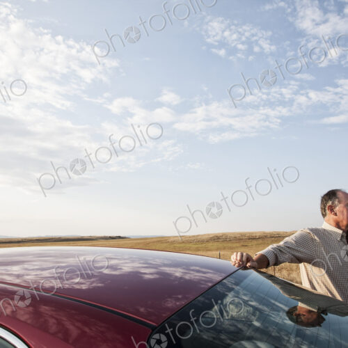 Caucasian man and his car parked along a highway