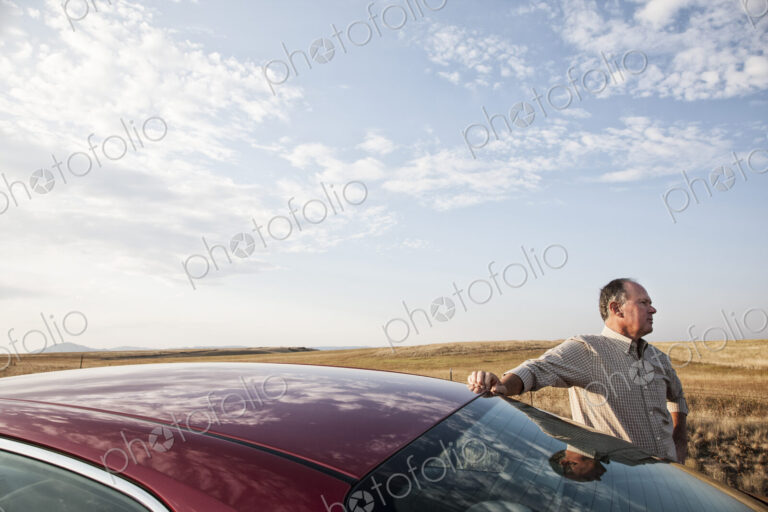 Caucasian man and his car parked along a highway