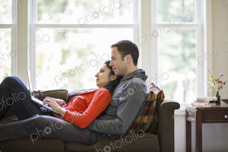 Caucasian man and mixed race caucasian woman using a laptop computer while sitting on…