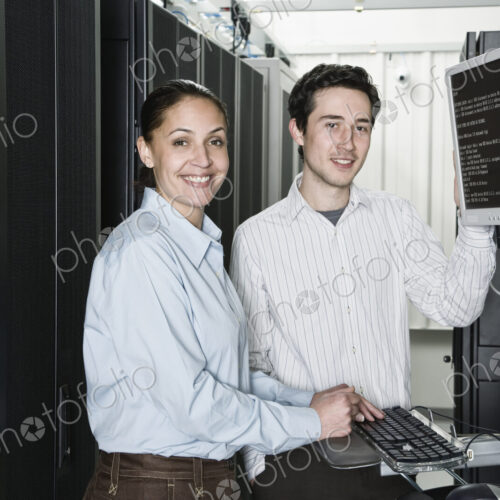 Caucasian man and woman computer techniciians checking data on computer servers in a…