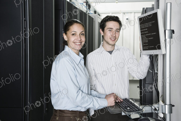 Caucasian man and woman computer techniciians checking data on computer servers in a…