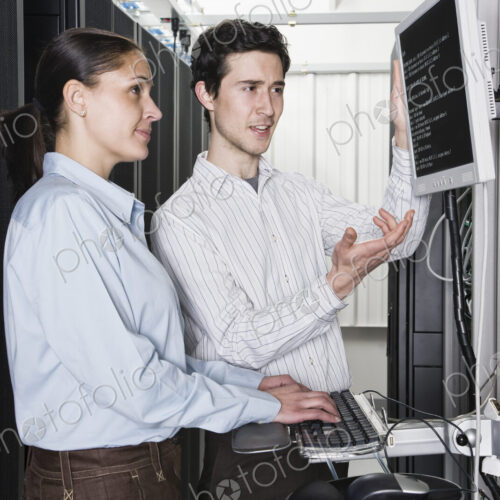 Caucasian man and woman computer techniciians checking data on computer servers in a…