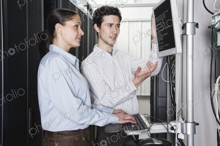 Caucasian man and woman computer techniciians checking data on computer servers in a…