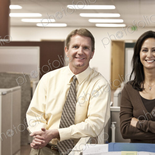 Caucasian man and woman executives in cubicle area of new office space Caucasian man and woman executives in cubicle area of new office space