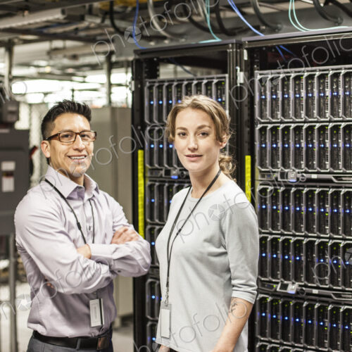 Caucasian man and woman technicians in a large computer server farm. Caucasian man and woman technicians in a large computer server farm.