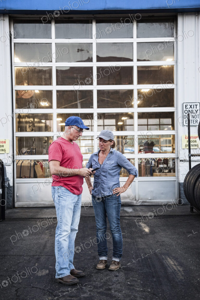 Caucasian man and woman truck drivers in front of an entrance bay at a truck stop…