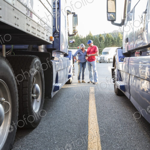 Caucasian man and woman truck driving team going over data on a cell phone while… Caucasian man and woman truck driving team going over data on a cell phone while…
