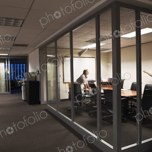 Caucasian man and woman working after hours in an office conference room. Caucasian man and woman working after hours in an office conference room.
