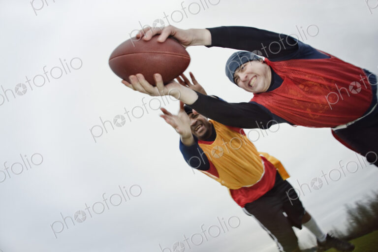 Caucasian man being tackled by an opponent,and diving with arms outstretched to score,…