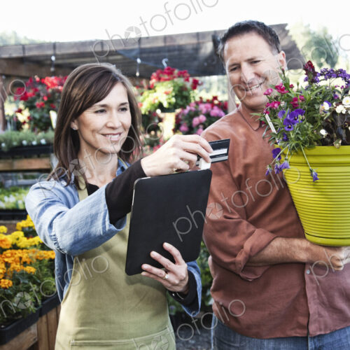 Caucasian man buying plants with a credit card at a nursery owned by a caucasian woman… Caucasian man buying plants with a credit card at a nursery owned by a caucasian woman…