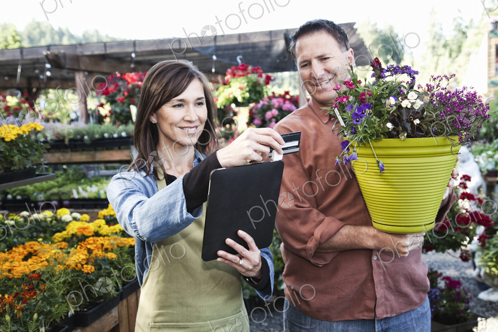 Caucasian man buying plants with a credit card at a nursery owned by a caucasian woman…