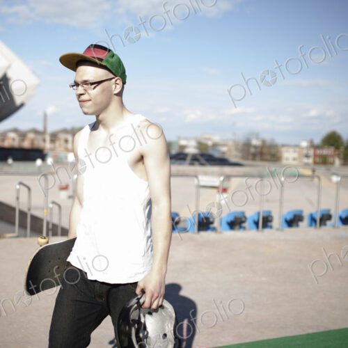 Caucasian man carrying skateboard near stadium