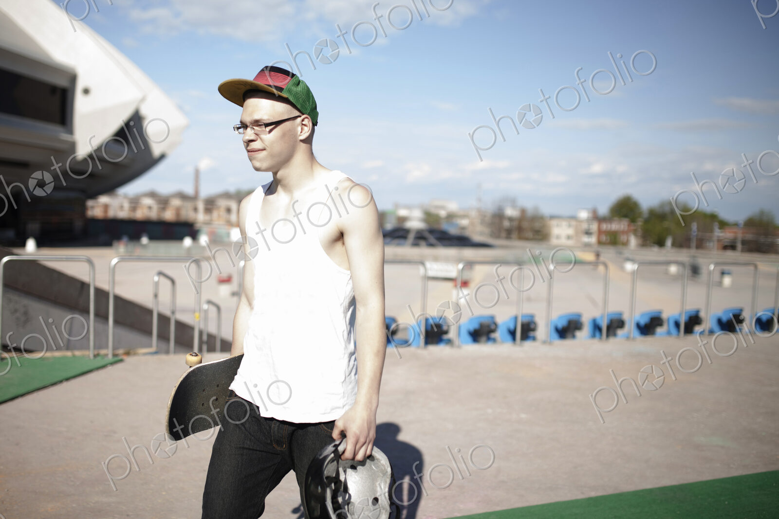 Caucasian man carrying skateboard near stadium