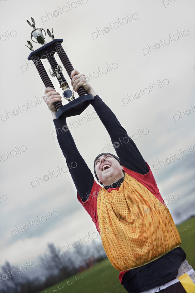 Caucasian man celebrating a sporting event win with a trophy.