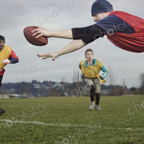 Caucasian man diving over the score line holding a football during an non-contact flag… Caucasian man diving over the score line holding a football during an non-contact flag…
