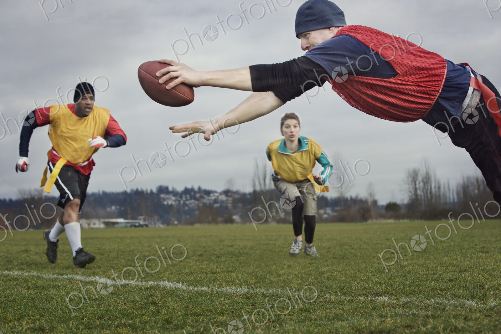 Caucasian man diving over the score line holding a football during an non-contact flag…