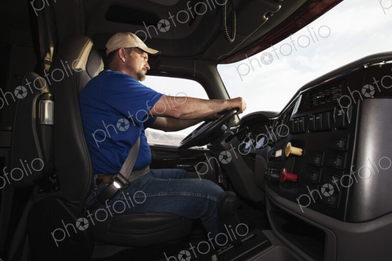 Caucasian man driver in the cab of a commercial truck.