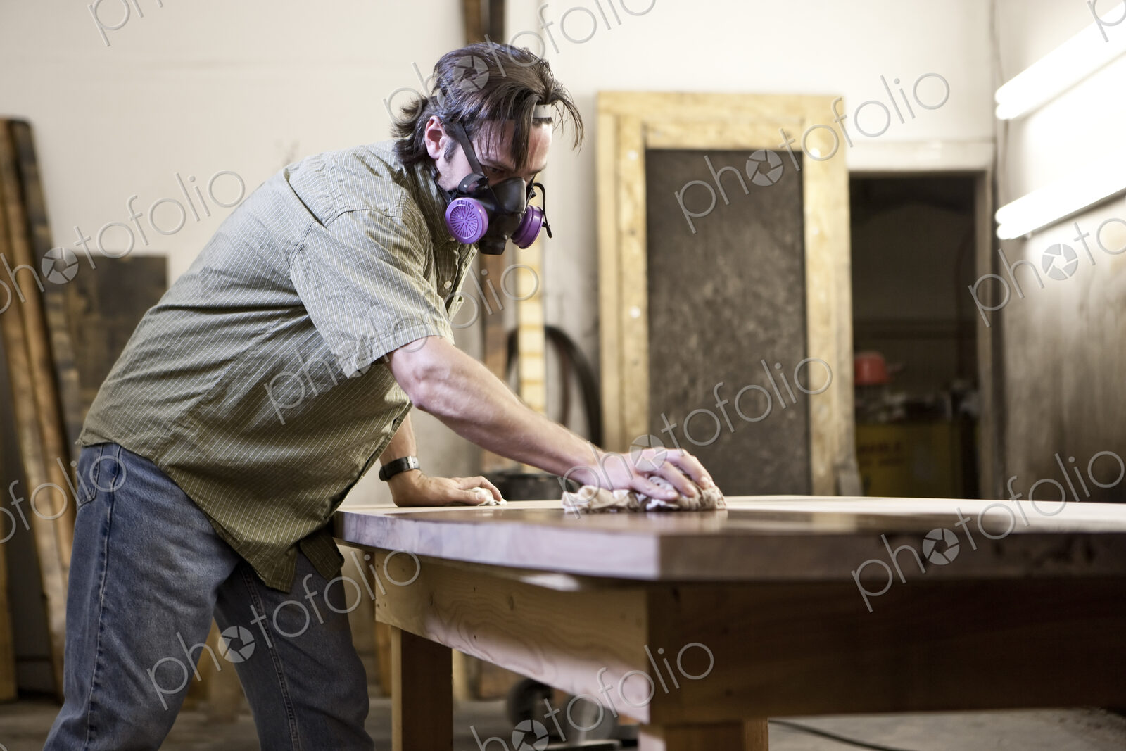 Caucasian man factory worker applying finish stain to the top of a table in a…