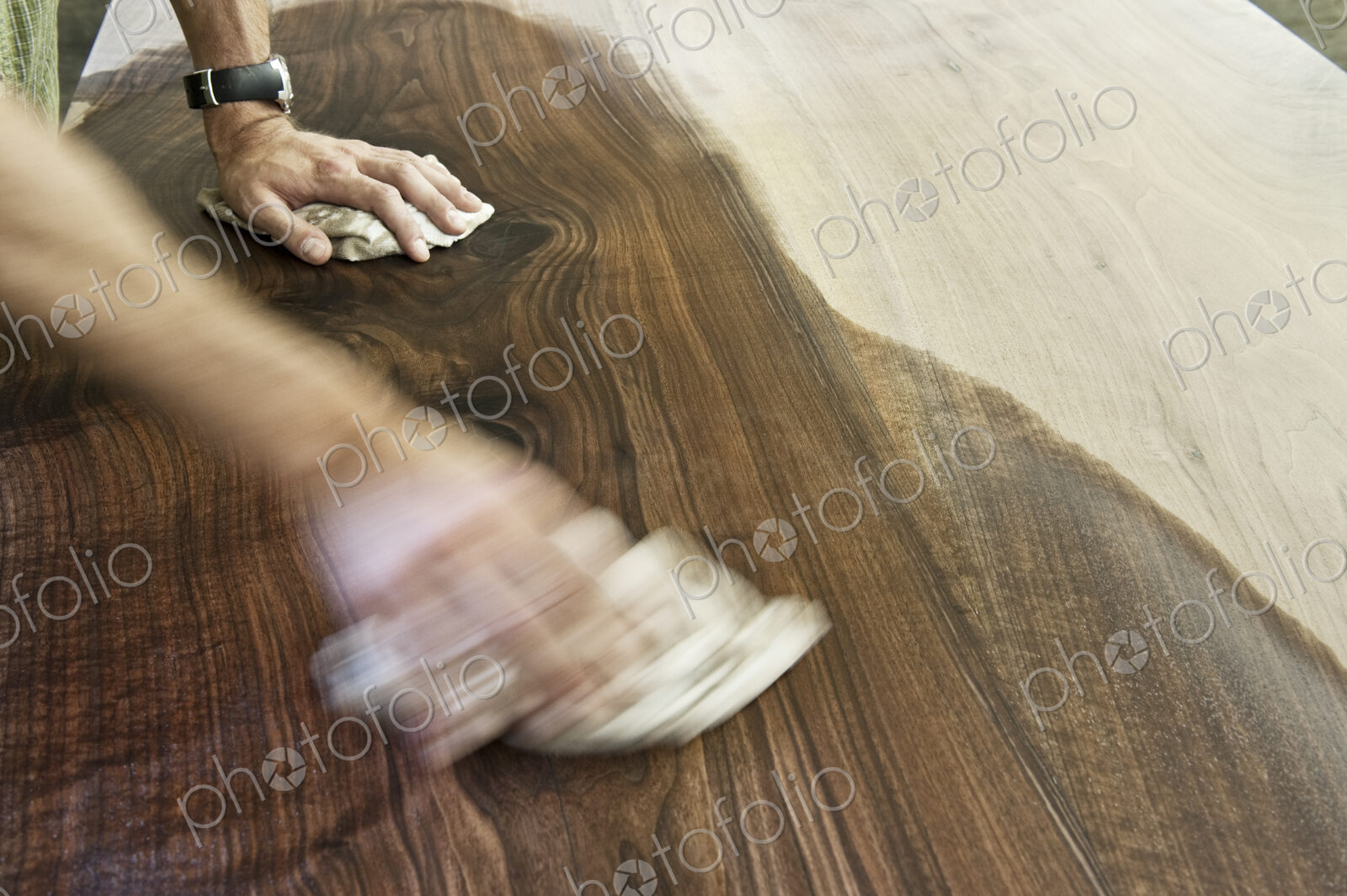 Caucasian man factory worker applying finish to a recycled wood table top in a…