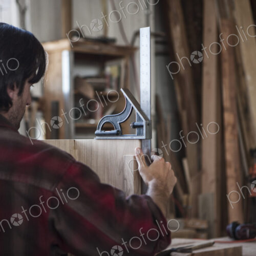 Caucasian man factory worker checking square measurements on a wooden part in a…